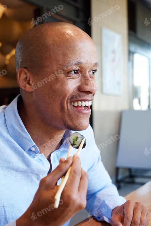 Preview: smiling african man enjoying eating sushi