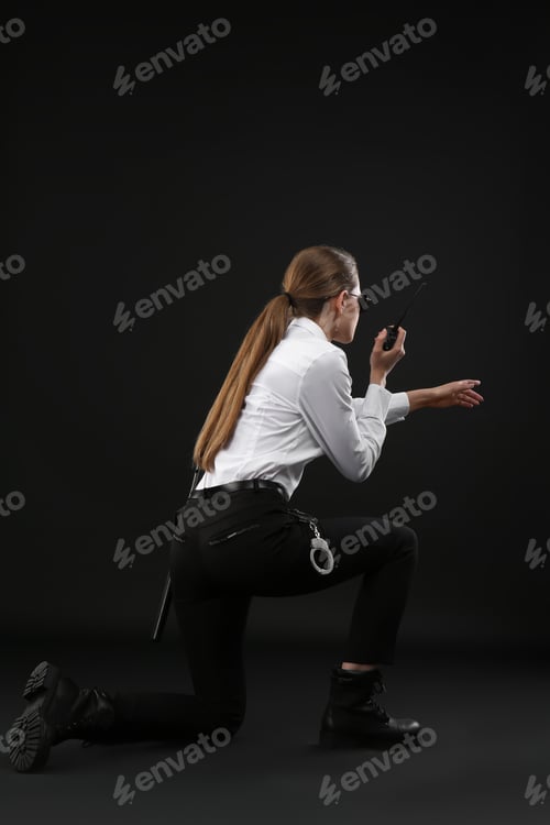Preview: Female security guard using portable radio transmitter on dark background