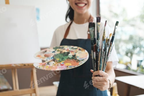 Preview: A close-up of the artist hands wearing an apron smeared with paint.