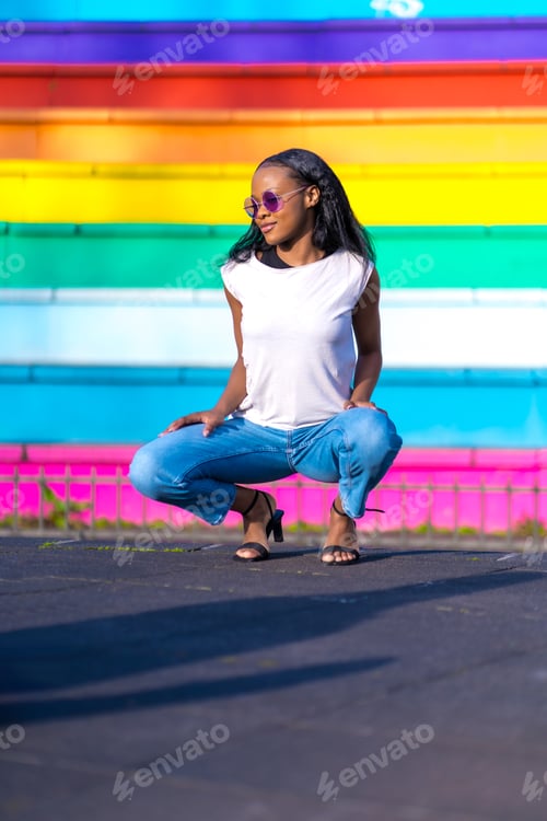 Preview: Young casual african woman squatting on an urban park