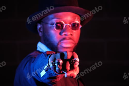Preview: Stylish black guy in sunglasses showing fist in studio