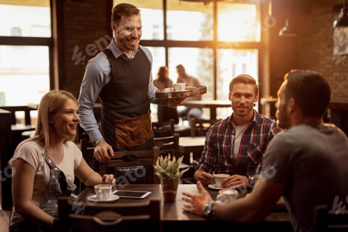 Preview: Young happy waiter serving group of friends in a coffee shop.