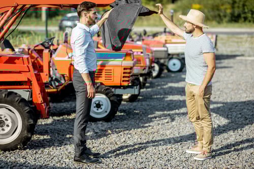 Preview: Agronomist with salesman near tractor at the agricultural shop