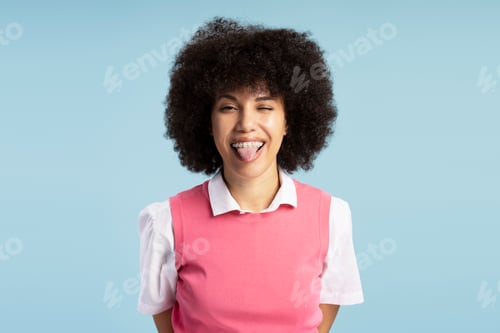 Preview: Playful young woman sticking out tongue with dental braces on blue background