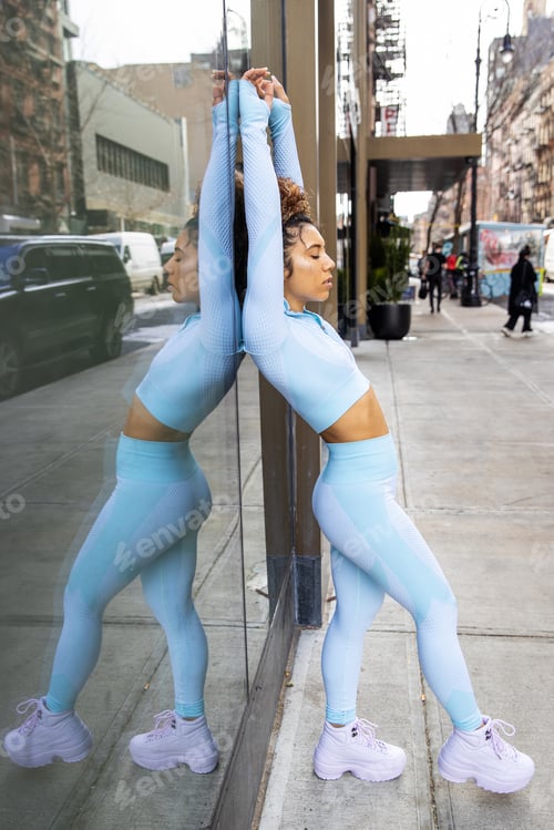 Preview: Mixed race woman wearing powder blue fitness clothes exercises outside on city sidewalk