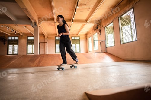 Preview: Unidentified young woman in casual sports clothing learning skateboarding trying to balance