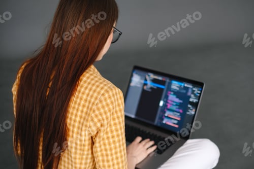 Preview: Young woman mobile developer writes program code on a computer, programmer work.