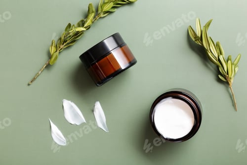 Preview: Glass jars of moisturizing cream and plants on green background. Concept of natural cosmetics