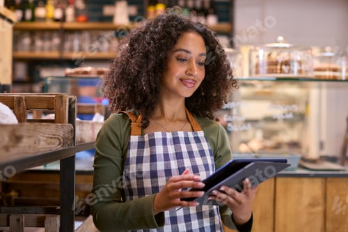 Preview: Smiling Young Woman Wearing Apron Working In Food Shop Using Digital Tablet