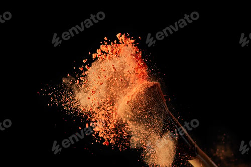 Preview: cosmetic brush with colorful orange powder explosion on black background