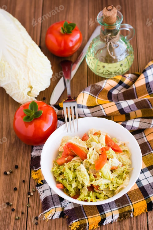 Preview: Ready-to-eat salad of tomatoes and Peking cabbage in a plate, vegetables and a bottle of oil