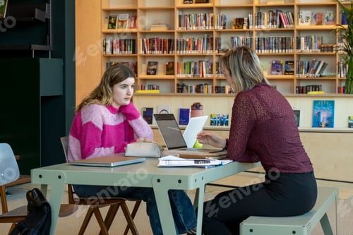 Preview: Two people in a focused study session at a library table.