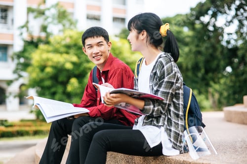 Preview: Male and female students sitting and reading books on the stairs.