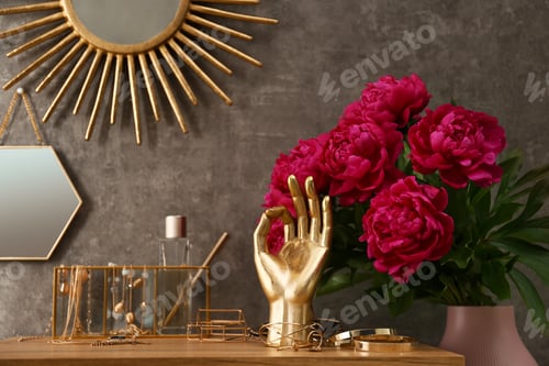 Preview: Composition with gold accessories and flowers on dressing table near grey wall