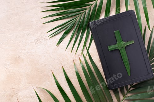 Preview: Palm Sunday concept. Palm cross on open Holy Bible and palm leaves. Reminder of Jesus sacrifice and