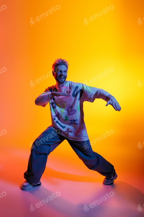 Preview: Dynamic young man showcasing dance moves against a vibrant orange and purple backdrop