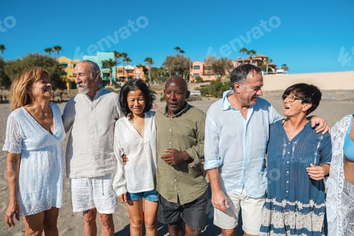 Preview: Happy senior people having fun walking on the beach at sunset wearing summer clothes