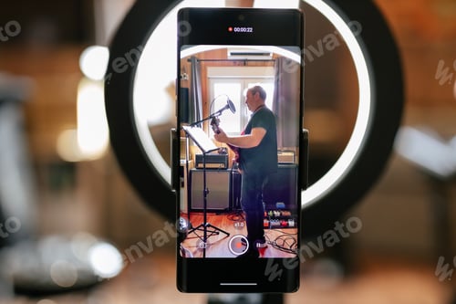 Preview: Modern smartphone on tripod recording video of man playing guitar