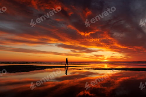 Preview: silhouette person against background beautiful sunset sky on ocean, reflection rays sun in water