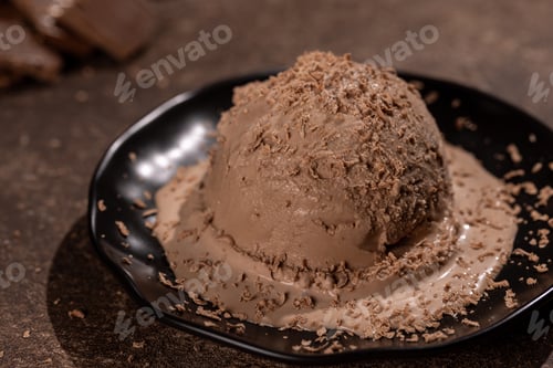 Preview: Scoop of chocolate ice cream with chocolate sprinkles on a black plate