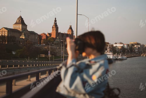 Preview: Woman Photographing Cityscape from Bridge at Sunset
