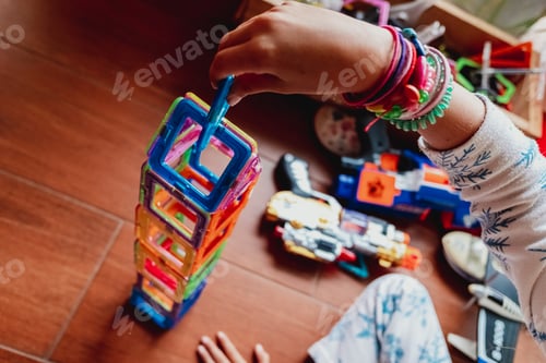 Preview: Little girl developing her skill by placing the last piece of a construction with plastic blocks.