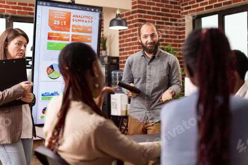 Preview: Executive manager standing beside monitor showing marketing graphs