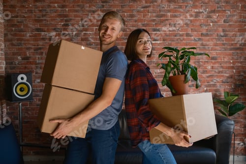 Preview: Couple happily carrying boxes into their new home during a moving day