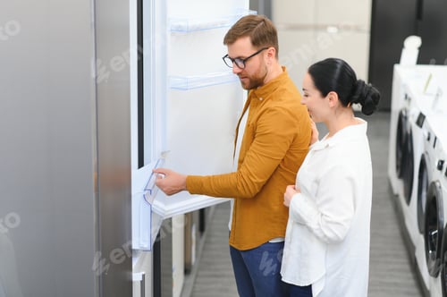 Preview: couple, satisfied customers choosing fridge in appliances store
