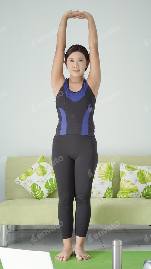 Preview: asian woman practicing yoga at home doing warm up hand movement
