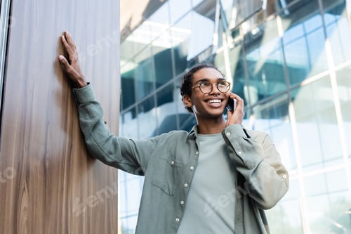 Preview: happy and stylish african american man talking on mobile phone outdoors