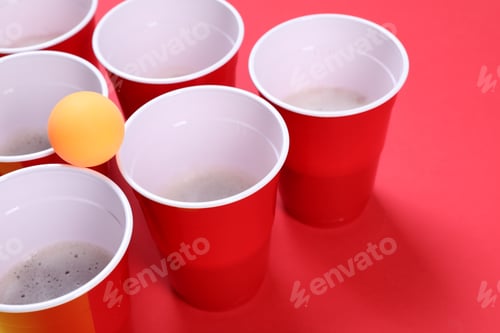 Preview: Plastic cups and ball for beer pong on red background