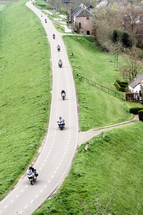 Preview: Road going over a green field with several motorbikers on it