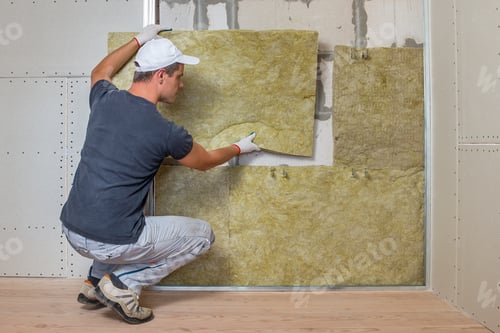 Preview: Worker insulating a room wall with mineral rock wool thermal insulation