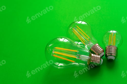 Preview: Light bulb on green paper background close up