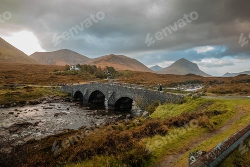 Preview: Arched-like bridge crossing over a river in a mountainous landscape