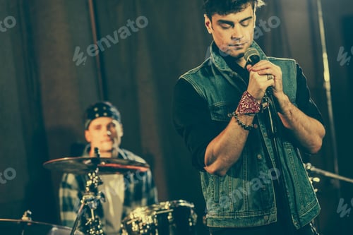 Preview: handsome man standing near microphone with closed eyes near drummer