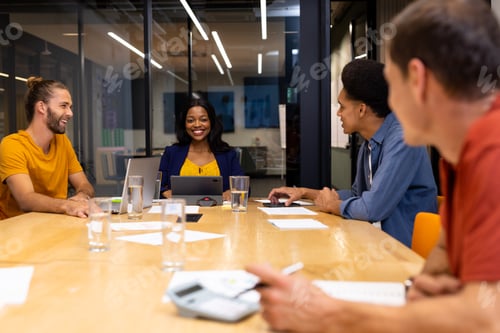 Preview: Happy diverse creative colleagues in discussion with laptop and tablet in meeting room