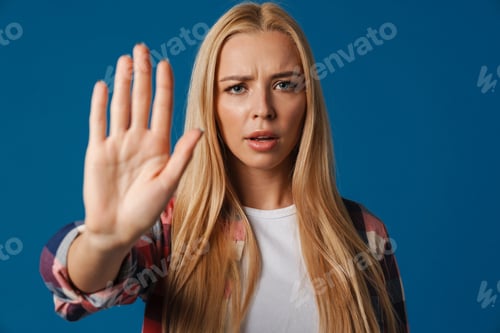 Preview: Blonde young displeased woman showing stop gesture at camera