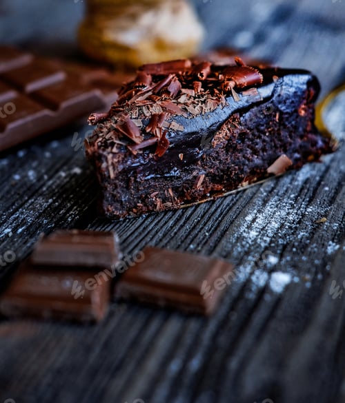 Preview: Gourmet slice of melty brownie and peaces of chocolate on the black table