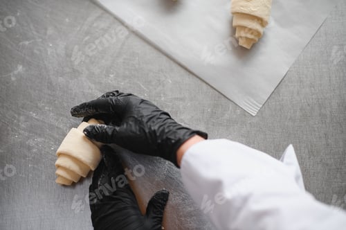 Preview: Baker making croissants in bakery: shaping dough for perfect pastry