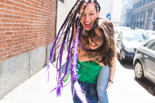 Preview: Women on city break playing piggyback in street, Milan, Italy