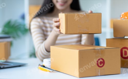 Preview: Startup small business entrepreneur of freelance woman using laptop and box to review orders online.