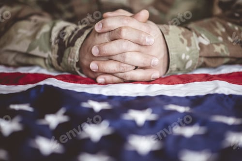 Preview: American soldier mourning and praying with the American flag in front of him