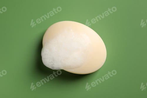Preview: Soap and fluffy foam on green background, top view