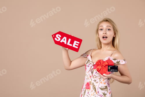 Preview: front view young female holding red present sale nameplate and bank card on brown background money