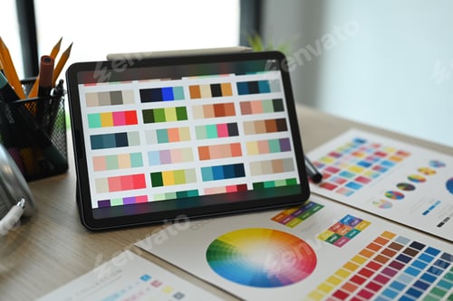 Preview: Creative designer workplace with digital table and color swatch on wooden table.