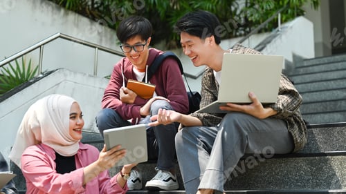 Preview: Happy students are sitting on college stairs and discussing their home assignment.