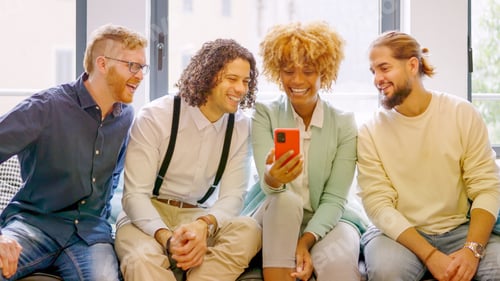 Preview: Coworkers using phone sitting relaxed during a break