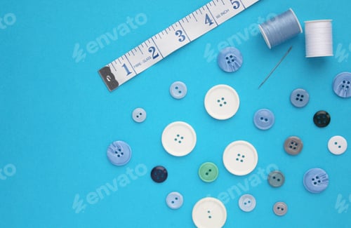 Preview: Sewing items flat lay style - blue and white buttons, a needle and spools of cotton thread